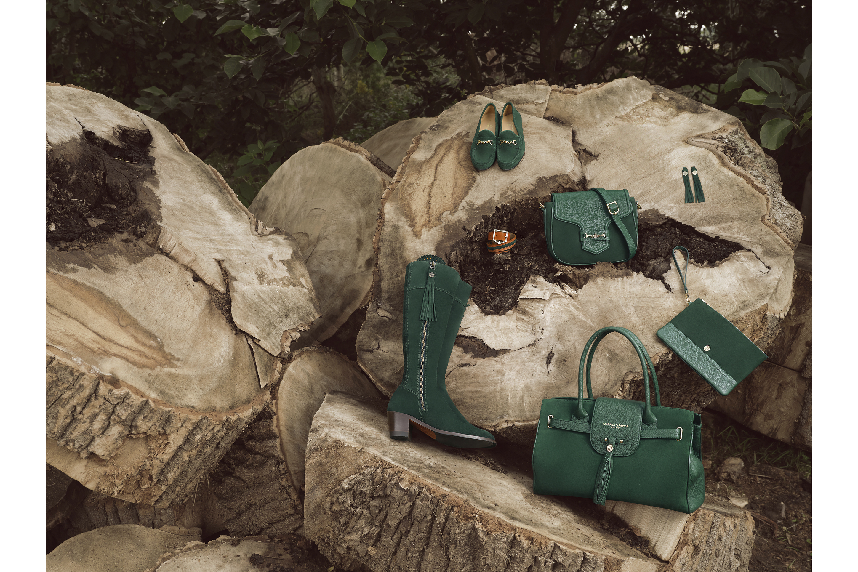 Green Hand bags and boots sitting on a wooden logs in a forest setting for a product photo shoot for Fairfax & Favour